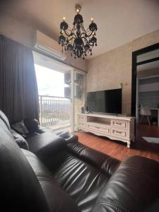 a living room with a leather couch and a television at Apt Casablanca East 2BR With Netflix and Pool in Jakarta