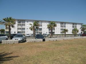 duży budynek z samochodami zaparkowanymi na parkingu w obiekcie Appartement T2 rénové, 4 couchages, parking, face plage, centre de Saint-Cyprien - FR-1-106-74 w mieście Saint-Cyprien