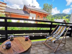 a table and a chair on a balcony with two coffee cups at Appartement rénové 4* aux Gets, 6 pers, parking inclus - FR-1-598-127 in Les Gets