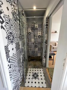 uma cabina de duche ao nível do chão com uma parede estampada em preto e branco em Charmant bungalow climatisé avec jacuzzi em Sainte-Clotilde