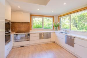 a large kitchen with white cabinets and windows at Anam Cara Gardens luxury Villa in Otaki