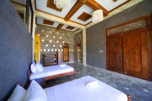 1 dormitorio con 2 camas y puerta de madera en Puri Uluwatu Villas en Uluwatu