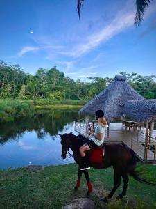 a woman riding a horse next to a pond at Lagoon Village B&B y SPA in Tarapoto