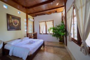 a bedroom with a bed in a room with windows at Puri Uluwatu Villas in Uluwatu