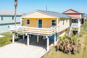 a small yellow house with a wooden porch at SUNNY DAZE Walk to Beach 2 Decks Pet Friendly Has a Mini Bar in Galveston