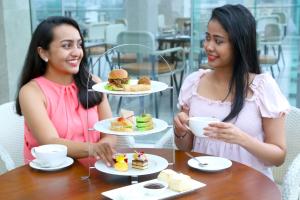 Due donne sedute a un tavolo con piatti di cibo di Courtyard by Marriott Colombo a Colombo
