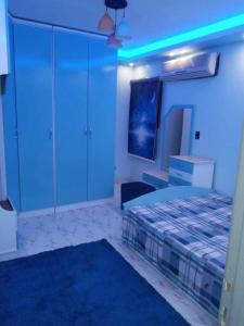 - une chambre avec un lit, une télévision et des lumières bleues dans l'établissement شقة مفروشة سوبر لوكس بالمريوطية هرم, au Caire