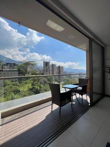 balcón con mesa y sillas y ventana grande en Apartamento con full entretenimiento, en Medellín