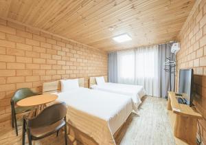 a room with two beds and a table and a tv at Jeju Healing Resort in Jeju