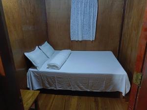 een klein bed met witte lakens en kussens in een kamer bij Rita's Homestay in Talap