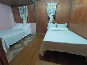 een slaapkamer met twee bedden en twee ramen bij Rita's Homestay in Talap