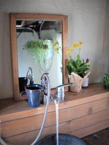 a bathroom sink with a faucet in front of a mirror at Bada Namu House 바닷가나무집 in Jeju