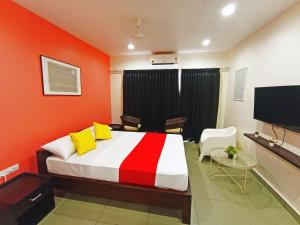 a bedroom with orange walls and a bed with yellow pillows at STAYMAKER White Sand Beach Resort in Honāvar