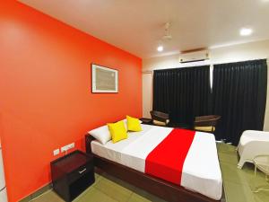 a bedroom with orange walls and a bed with yellow pillows at STAYMAKER White Sand Beach Resort in Honāvar
