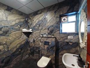 a stone bathroom with a sink and a toilet at STAYMAKER White Sand Beach Resort in Honāvar