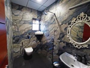 Baño de piedra con lavabo y espejo en STAYMAKER White Sand Beach Resort en Honāvar