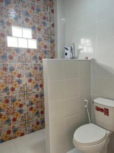 a bathroom with a toilet and a flower tile wall at บ้านสวนมะม่วงรีสอร์ท 