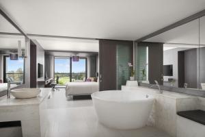 曼谷的住宿－曼谷素萬那普艾美高爾夫水療度假酒店，带浴缸和大镜子的大浴室