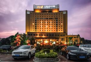 un edificio con dos coches estacionados frente a él en S&N Hotel Dalian, en Wafangdian