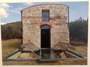 a building with a door in the middle of a field at Villa Pieve Vecchia in Campagnatico