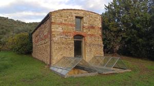 an old brick building with a door in the grass at Villa Pieve Vecchia in Campagnatico