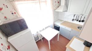 Una pequeña cocina con una mesa y un refrigerador blanco. en Teatra 32, en Daugavpils