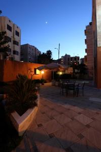 eine Terrasse mit Tischen und Stühlen in einer Stadt in der Nacht in der Unterkunft Barakat Hotel Apartments in Amman