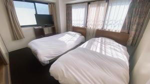 a hotel room with two beds and a television at Esperanza 204号室 in Tokyo