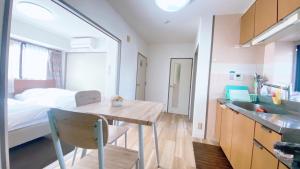 a room with a bed and a table and a kitchen at Esperanza 204号室 in Tokyo