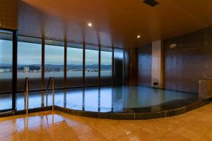 a swimming pool in a building with a view of the water at Hotel Ichibata in Matsue