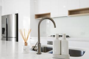 Un mostrador de cocina con dos botellas de jabón y un fregadero. en Oceanviews on Pearl, en Kingscliff