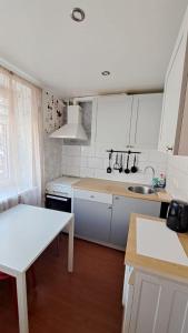 cocina con armarios blancos, fregadero y mesa en Teatra 32, en Daugavpils