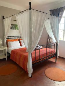 sypialnia z łóżkiem z baldachimem i białymi zasłonami w obiekcie Résidence Bleu Azur w mieście Grand Baie