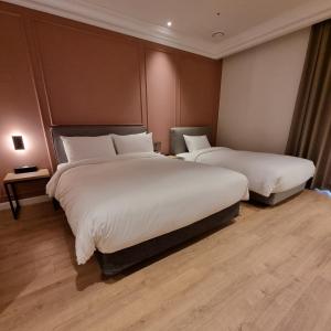 a hotel room with two beds with white sheets at Busan City Hotel in Busan