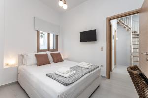a bedroom with a white bed and a tv on the wall at Cozy Comfy Town House in Naxos Chora