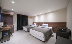 um quarto de hotel com duas camas e uma secretária em Hotel Egg em Busan
