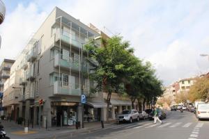 un edificio alto en una calle de la ciudad con coches aparcados en Apartamentos Pepita Bandert, en Cambrils