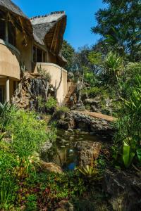 a house with a stream in front of a yard at Amanzi Lodge in Harare