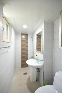 Baño blanco con lavabo y aseo en Sunnyhill Guesthouse Hongdae, en Seúl