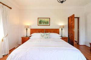 a bedroom with a large bed with white sheets at A Tuscan Villa Guest House in Fish hoek