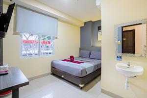 a bedroom with a bed and a sink and a mirror at City Biz Residence in Jakarta