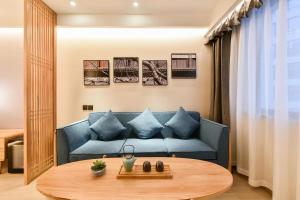 Atour Hotel Beijing Fuxingmen في بكين: غرفة معيشة مع أريكة زرقاء وطاولة