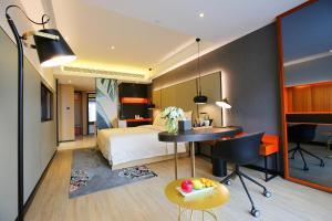 Cette chambre comprend un lit, un bureau et une table. dans l'établissement Atour S Hotel Chengdu Taikoo Li, à Chengdu