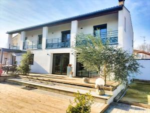 duży biały dom z drzewem przed nim w obiekcie Villa Moderne * Piscine privée 5x10 * Climatisation * Camargue w mieście Marsillargues +25 zdjęć