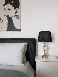 a bed with a lamp on a side table with a picture at Stylish Master Suite + Private Bathroom + TV FREE Parking Pet Friendly in Glenfield