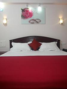 a bedroom with a red and white bed with a red blanket at Hotel Nambi in Madurai