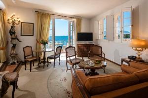 a living room with a couch and chairs and a table at Hotel Le Maquis in Porticcio