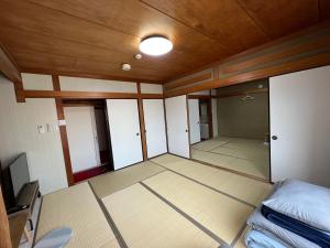 an empty room with a bed and a wooden ceiling at HOSTEL OE in Yoshinogawa