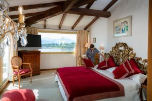 a man standing in a bedroom with a large bed at Hotel Le Maquis in Porticcio