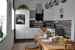a kitchen with white cabinets and a table with food on it at Ferienwohnungen in Losheim am See - Gästehaus am Bachlauf - in Losheim